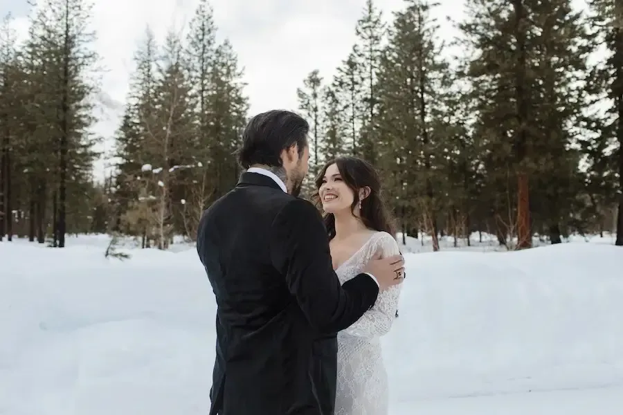 A bride and groom are dancing in the snow.