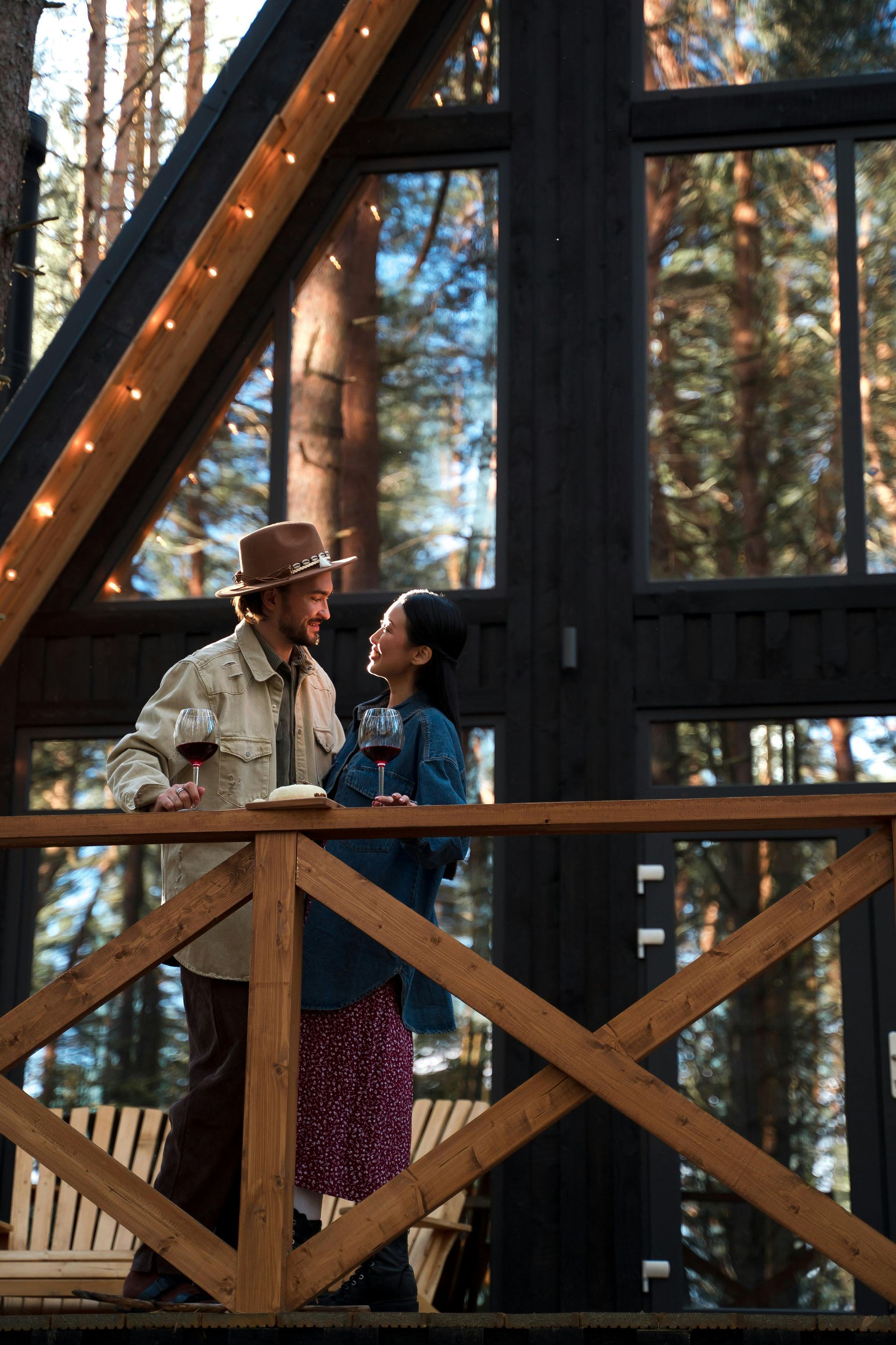 A man and a woman are standing on a balcony drinking wine.