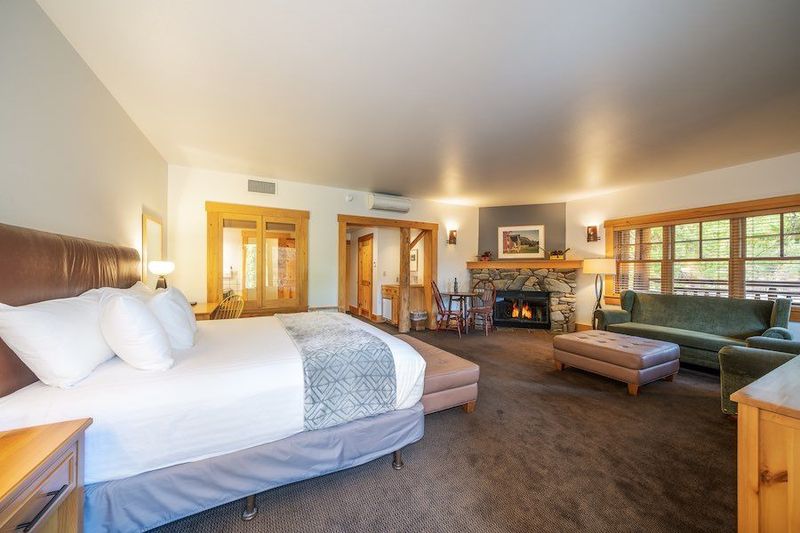 A hotel room with a king size bed , couch , and fireplace.