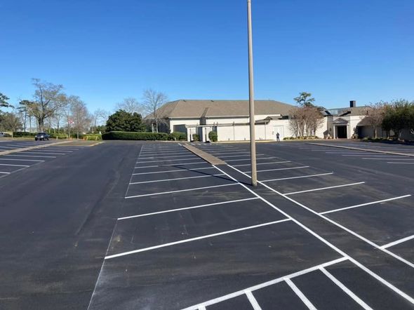 Empty parking lot with freshly painted white lines and a tall light pole in the center on a clear, sunny day. Empty parking lot with freshly painted white lines and a tall light pole in the center on a clear, sunny day.