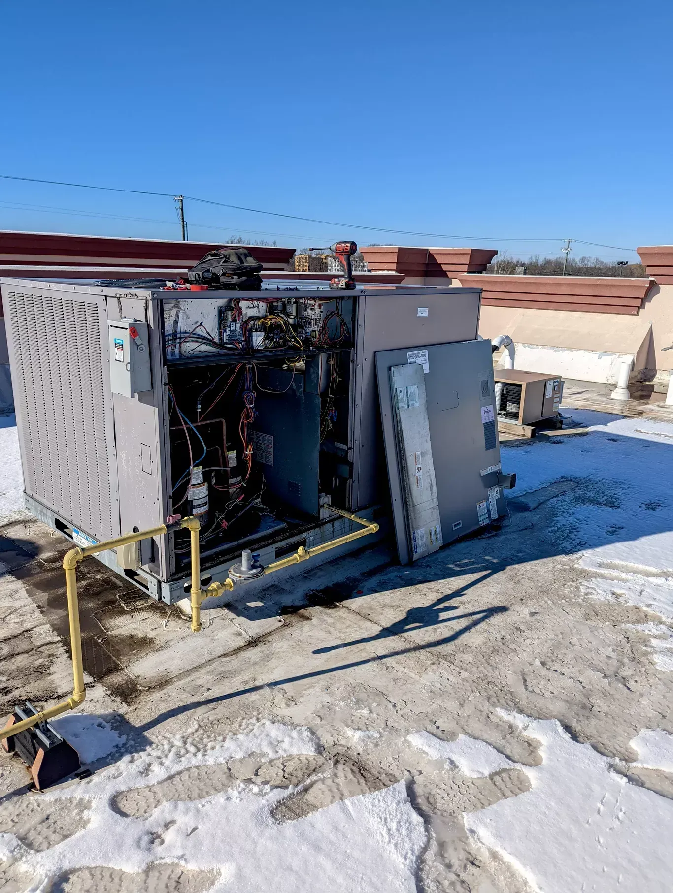 A large air conditioner is sitting on top of a snow covered roof.