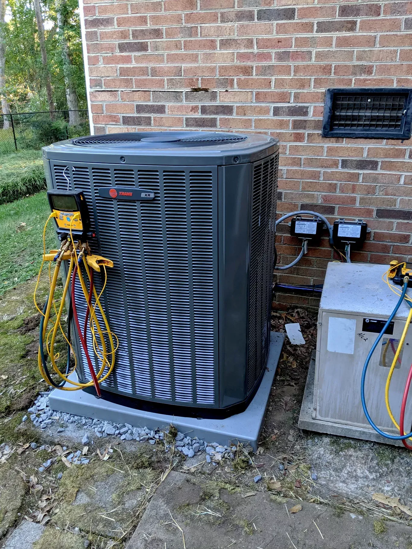 A large air conditioner is sitting on the side of a brick building.