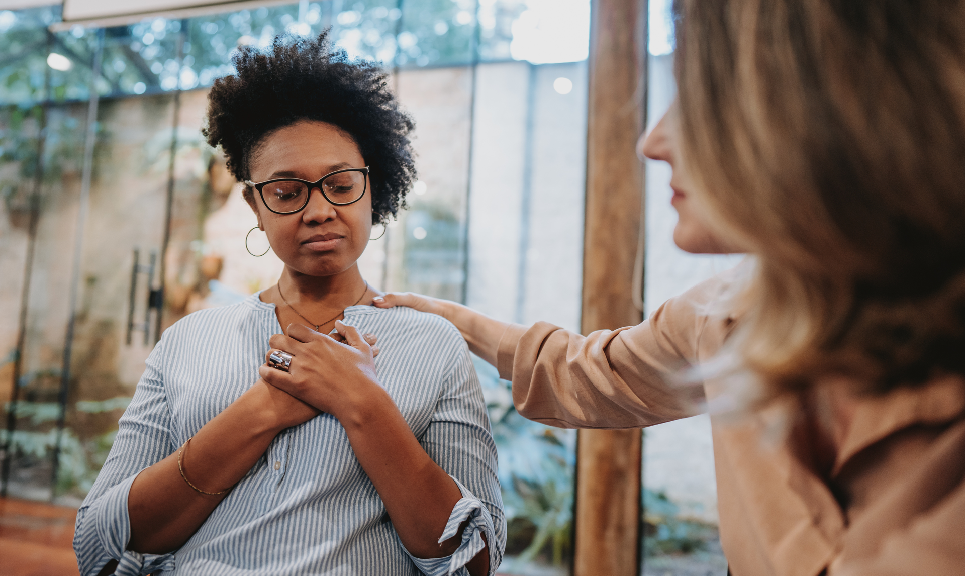 Woman comforted by another with hand on her shoulder, indoors. Woman comforted by another with hand on her shoulder, indoors.
