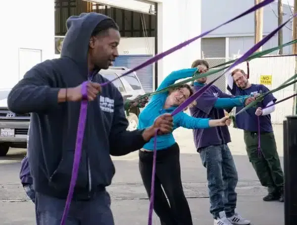 People stretching colorful bands outdoors in front of a building