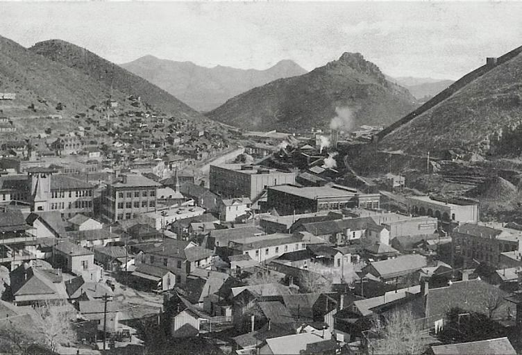 Black-and-white view of a mountain town with dense rooftops and buildings in a valley