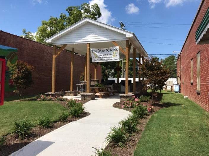 Brick walkway leading to a small white pavilion with a banner in a garden courtyard