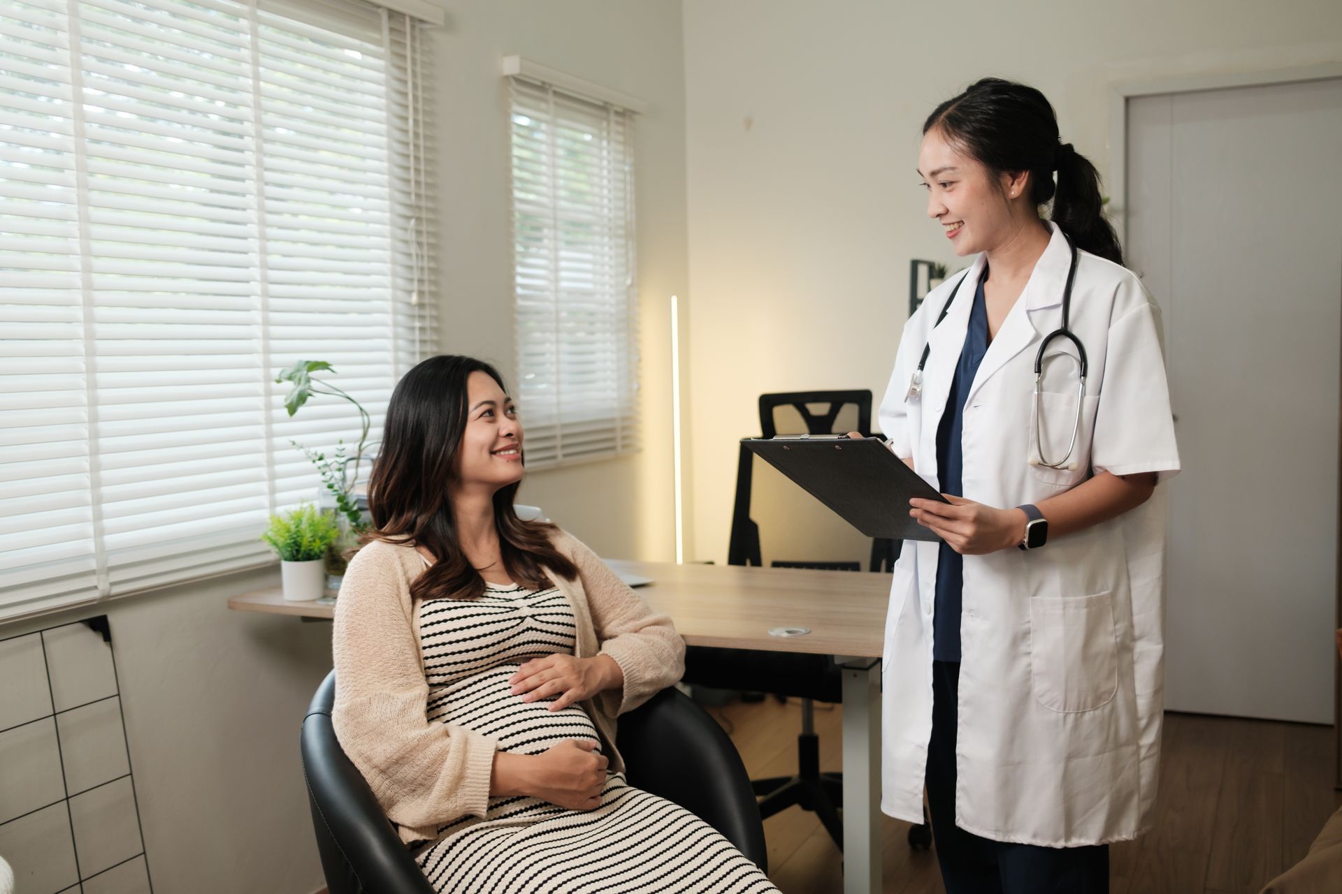 Prenatal visit with expectant mother consulting a doctor in a medical office.