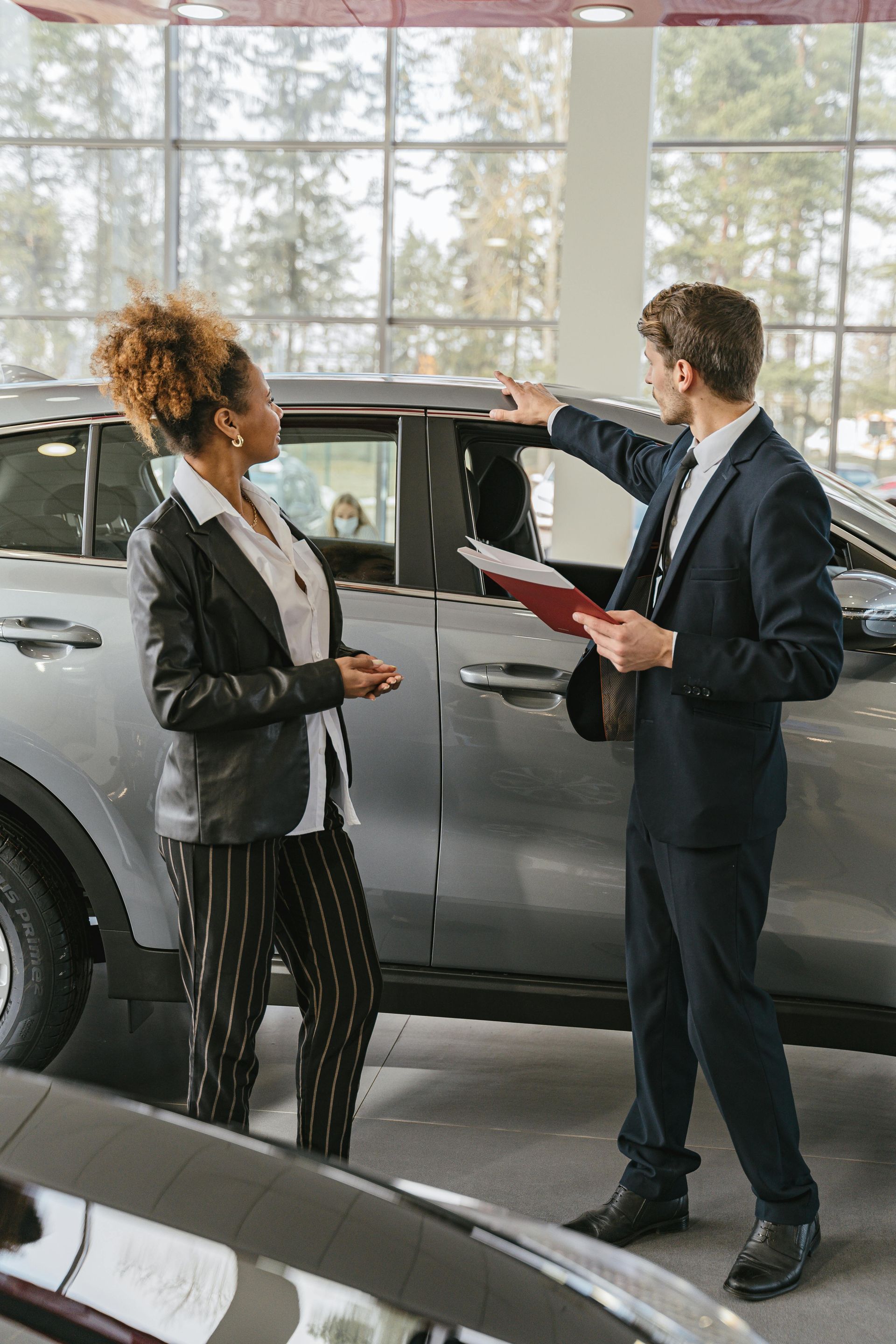 A man and a woman are standing next to a car in a car showroom. | Flickinger's Auto Service