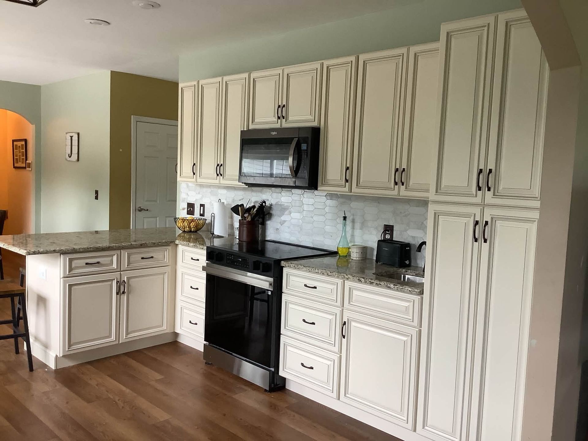 Bright kitchen with white cabinets, black appliances, and wood flooring.