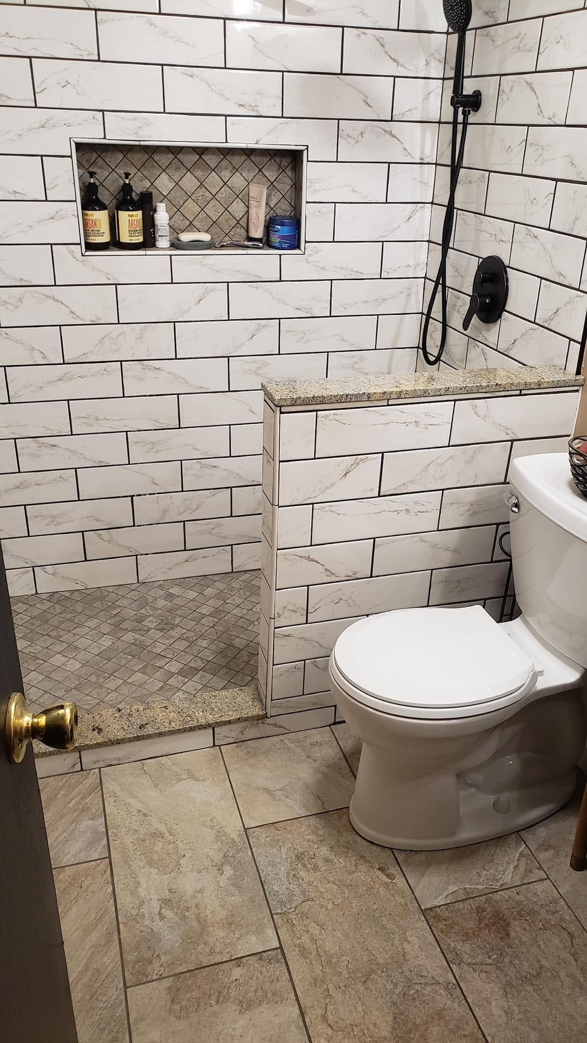Small tiled bathroom with toilet, walk-in shower, and built-in wall niche.