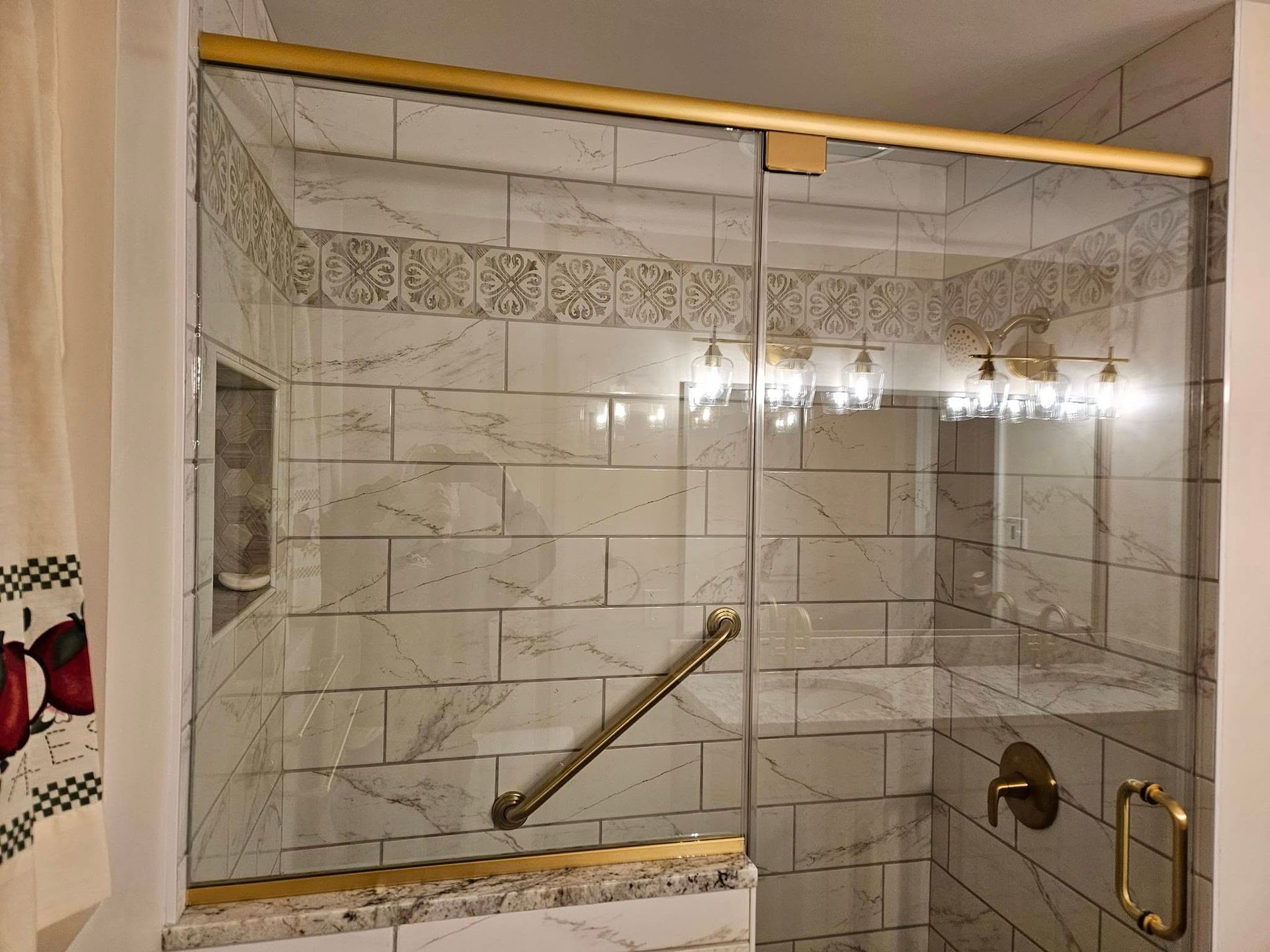 Glass shower stall with beige tile walls, chrome handle, and a diagonal grab bar