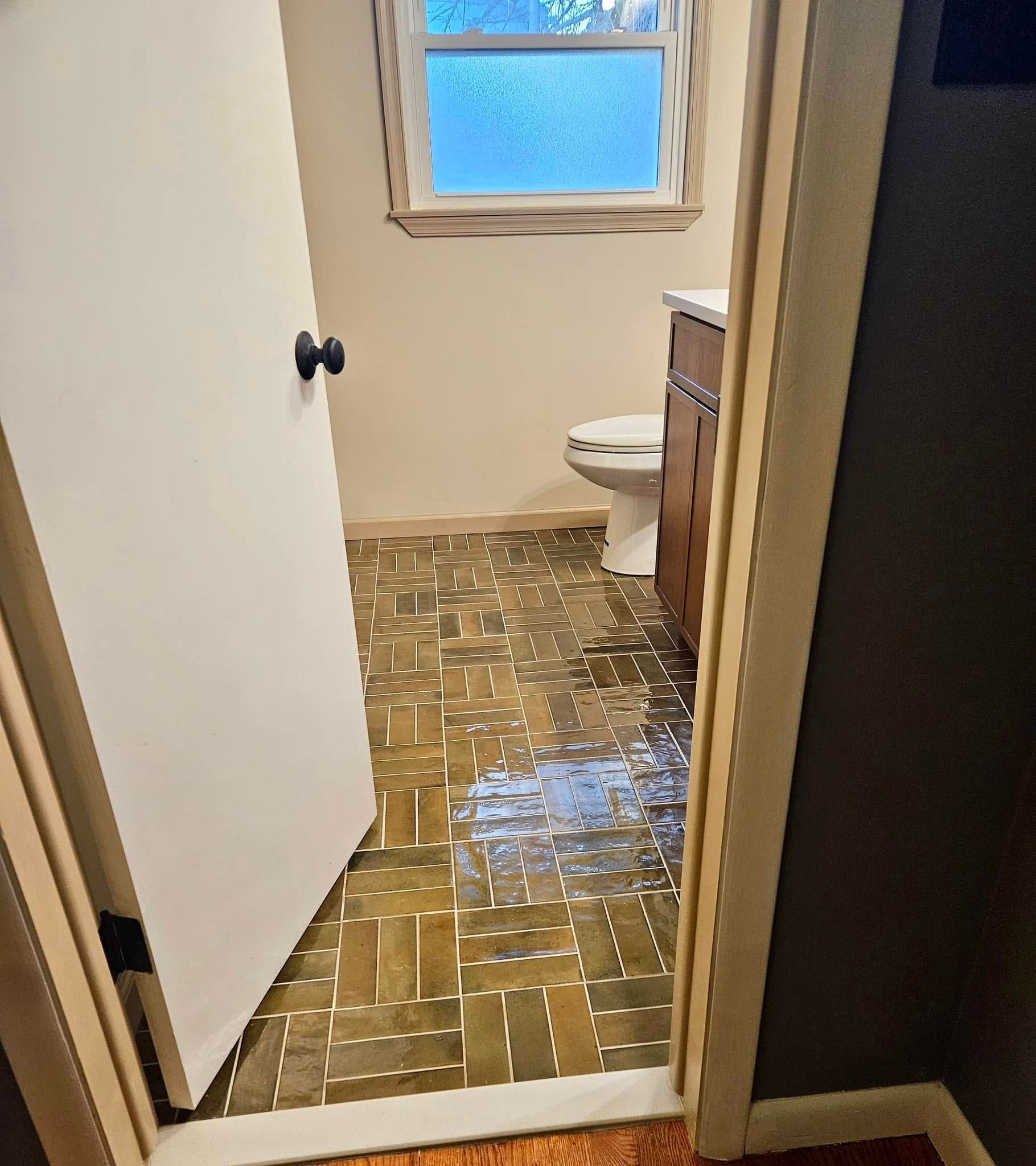Small bathroom with water covering the tile floor, seen through an open doorway.