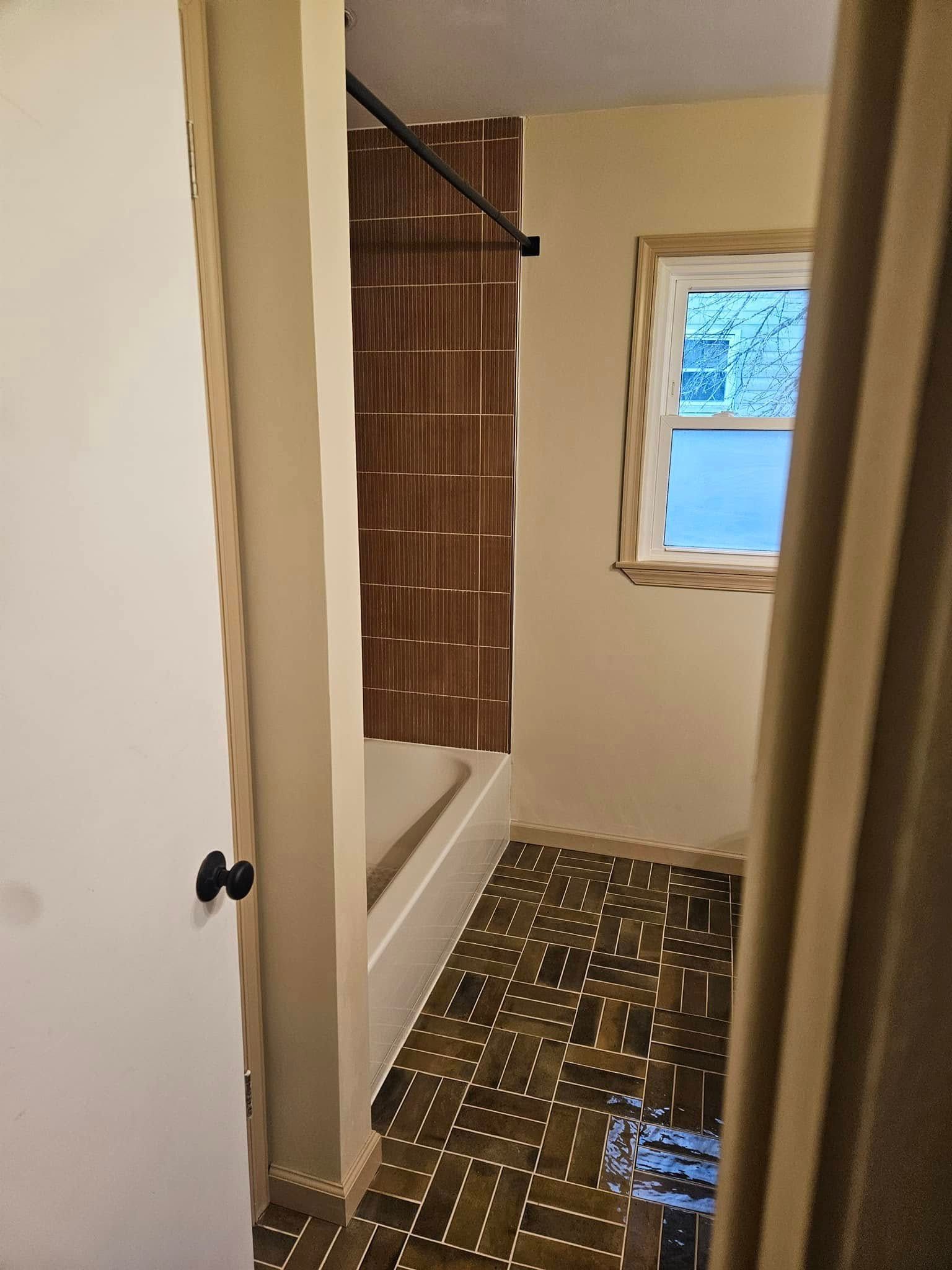 Small bathroom with a shower curtain, tiled floor, and a window letting in blue daylight.