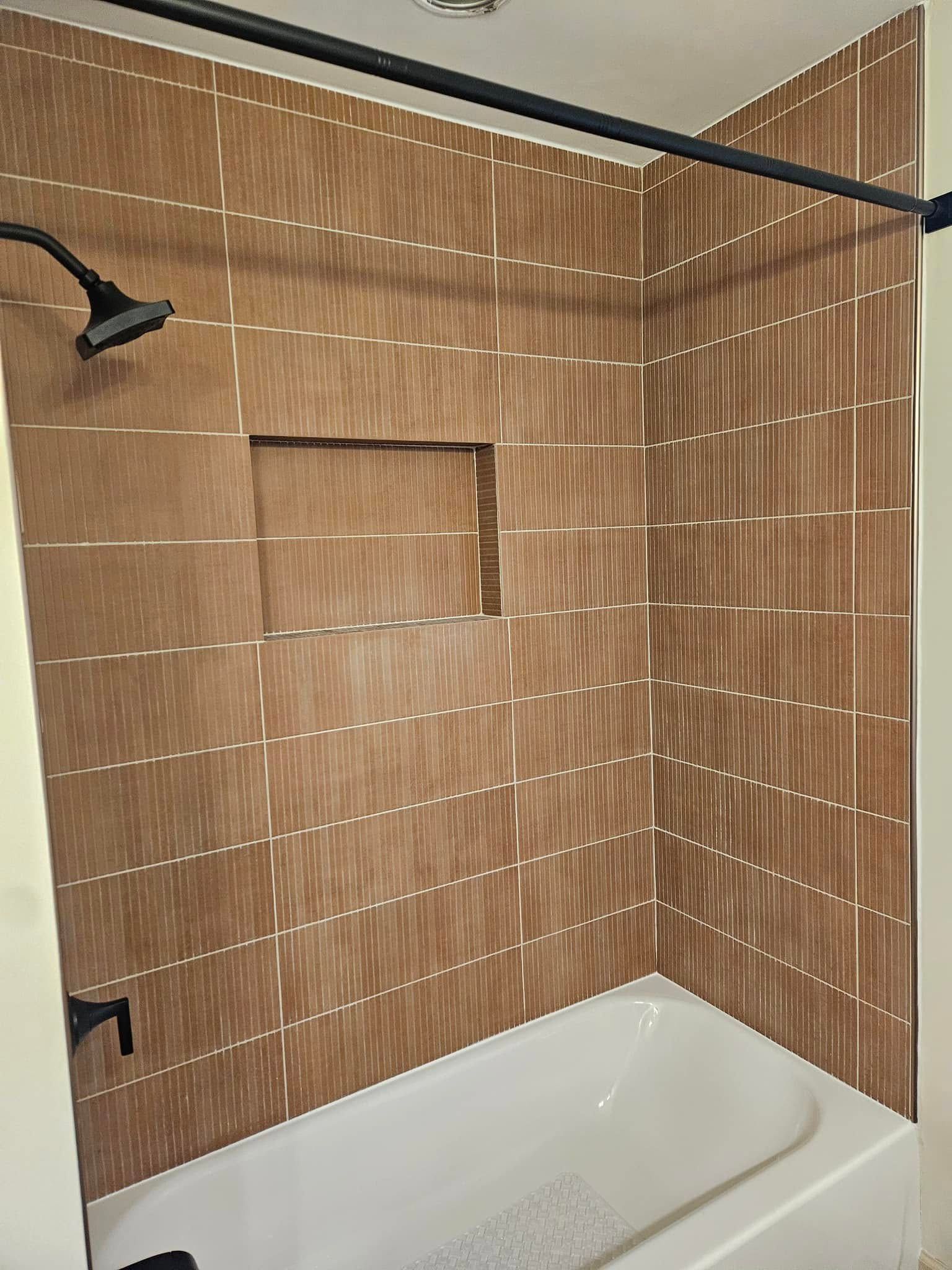 Bathroom shower with tan tile walls, black shower rod, and white tub.