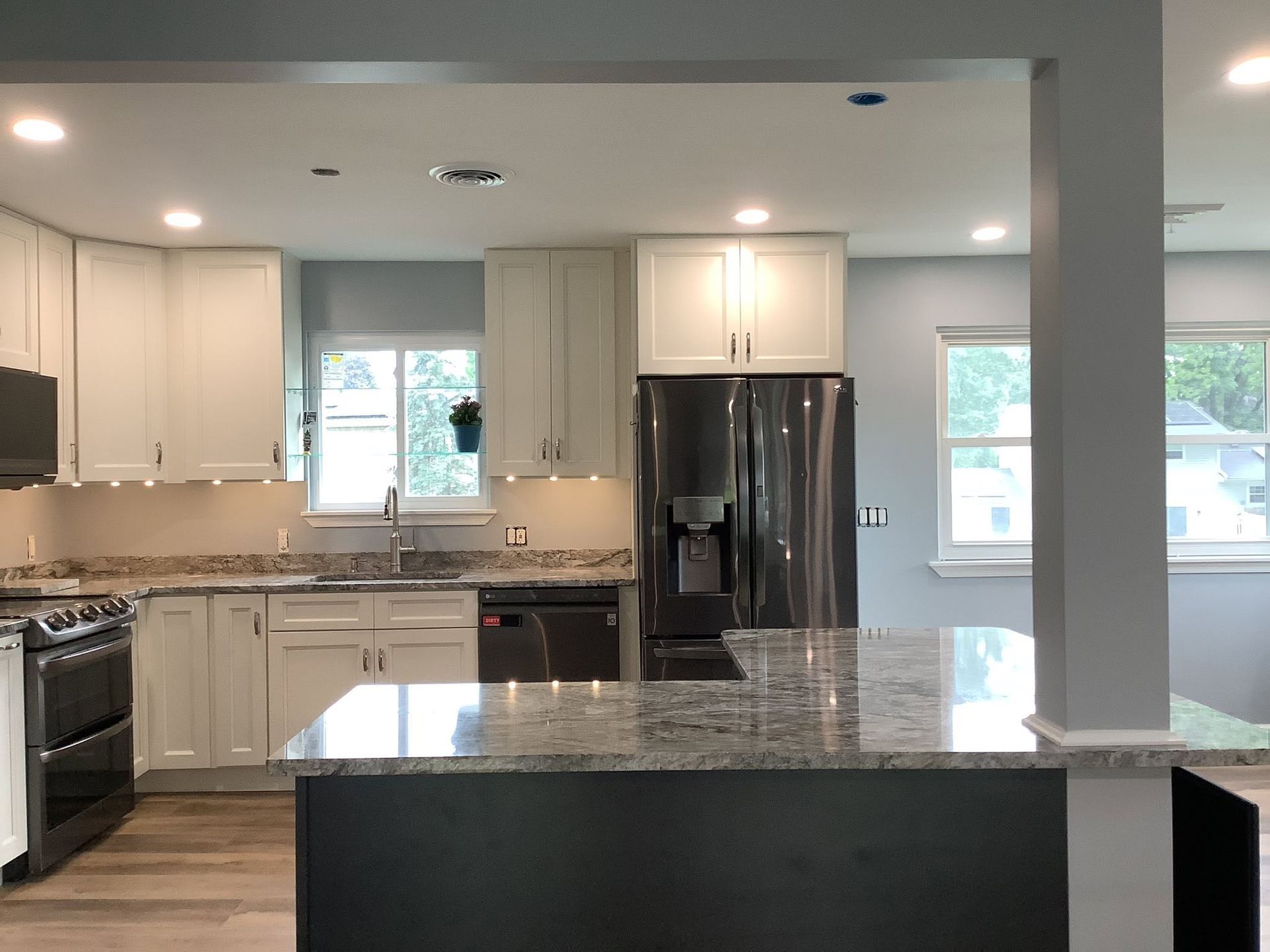 Bright modern kitchen with white cabinets, stainless steel appliances, and a black island countertop.