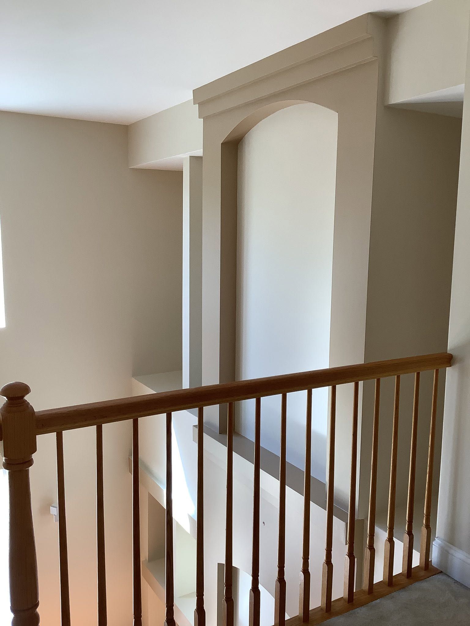 Interior hallway with wooden railing and a decorative arched wall niche.