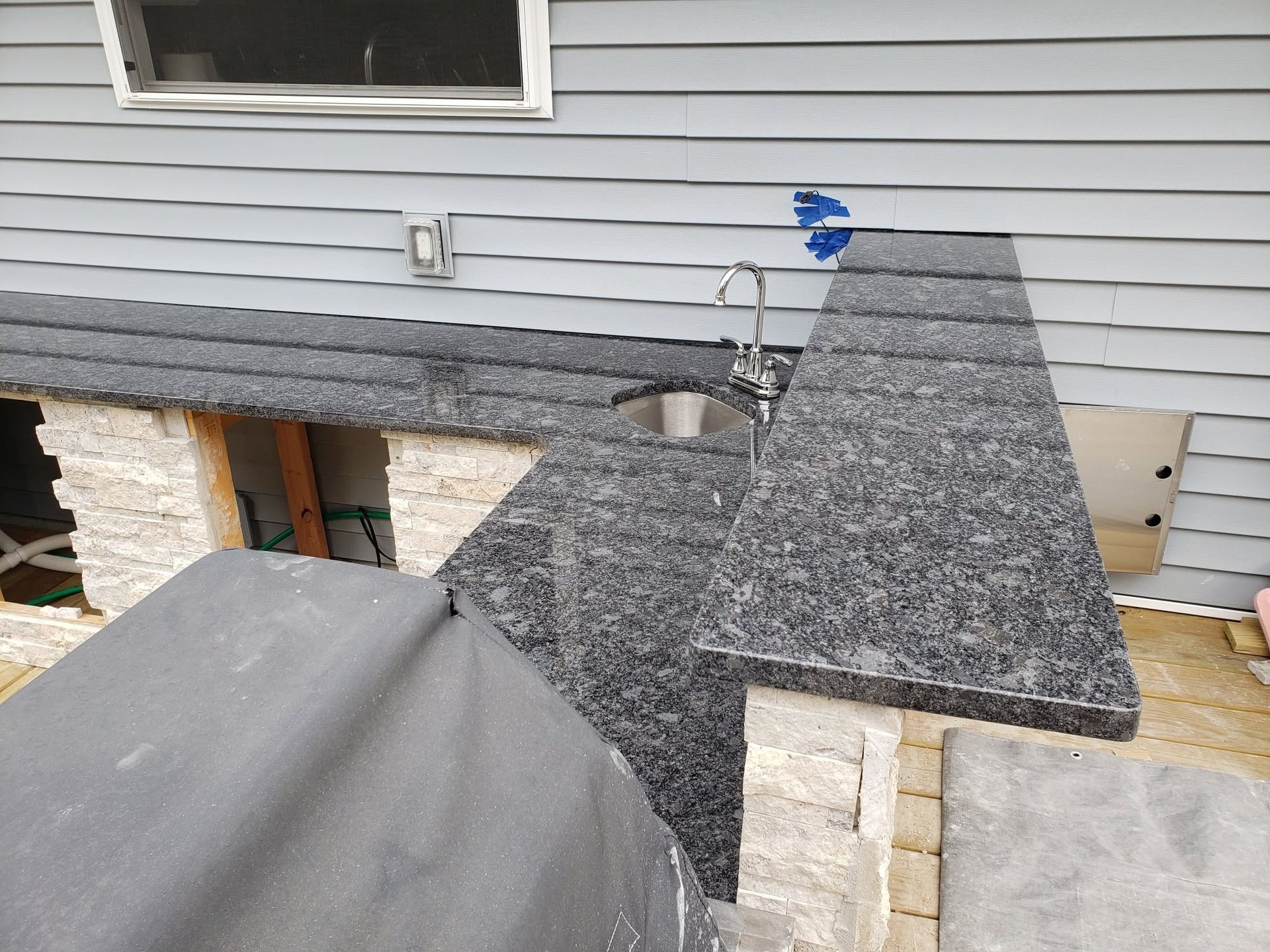 Roofing under construction with gray shingles and a vent pipe beside a house exterior