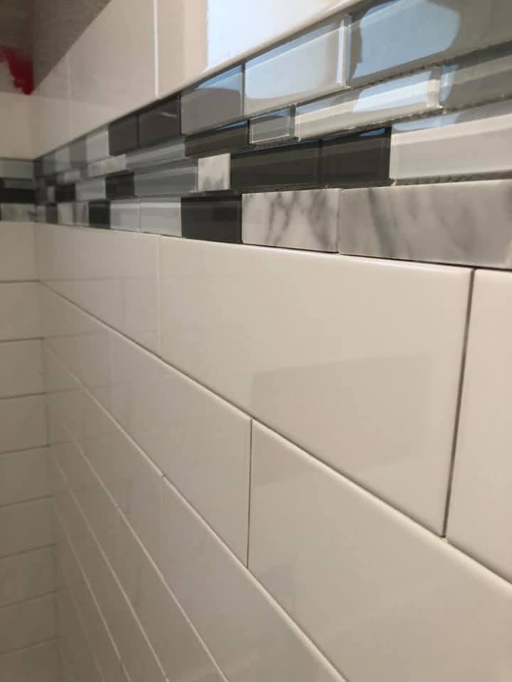 A bathroom wall with white tiles and black and gray tiles.