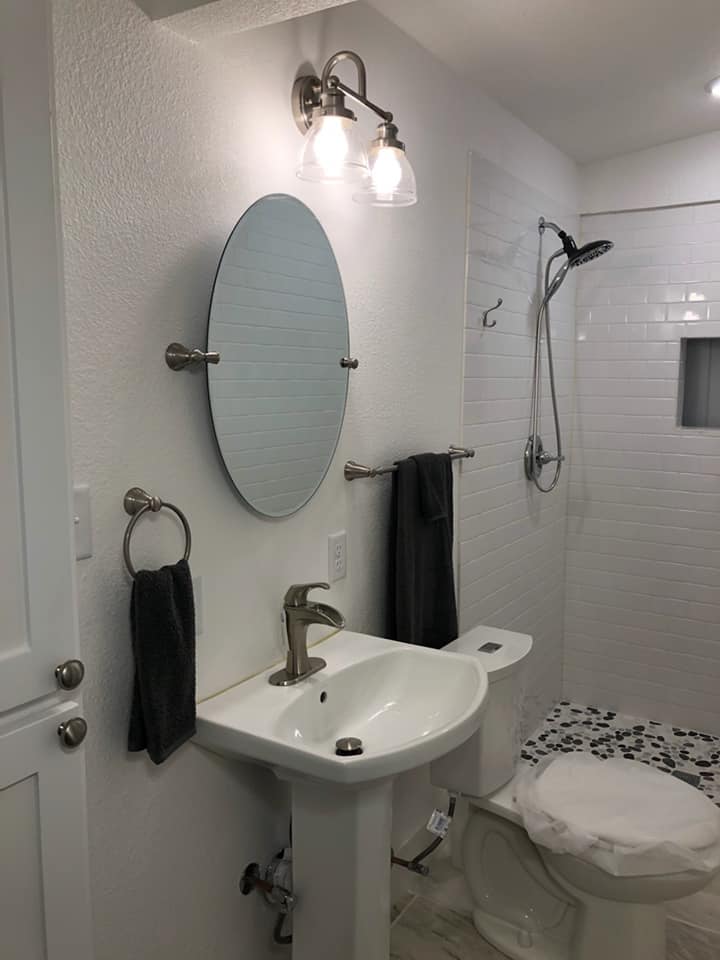 A bathroom with a sink , toilet , mirror and shower.