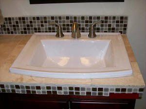 A bathroom sink is sitting on top of a tiled counter top.