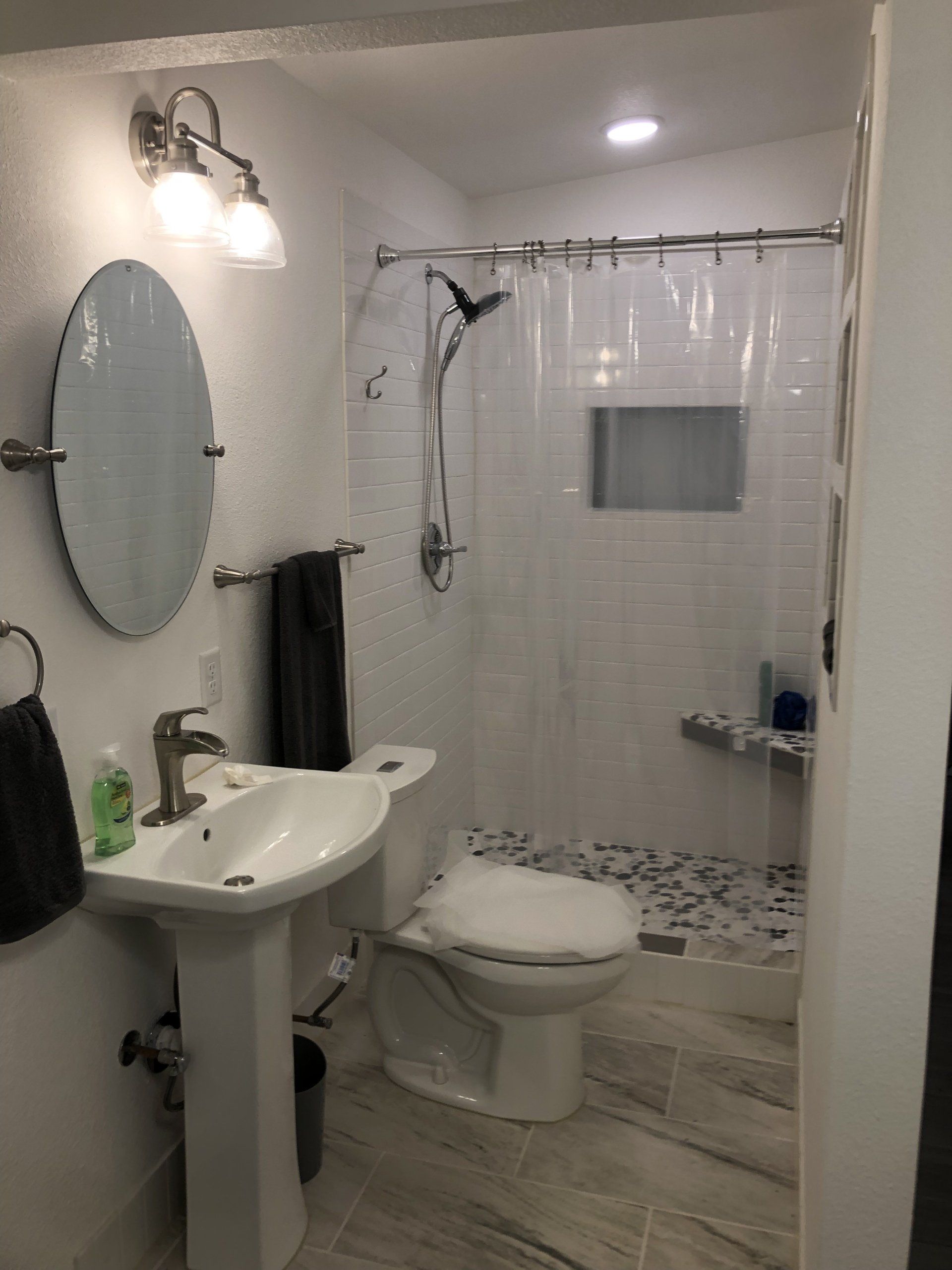 A bathroom with a toilet , sink , mirror and shower.