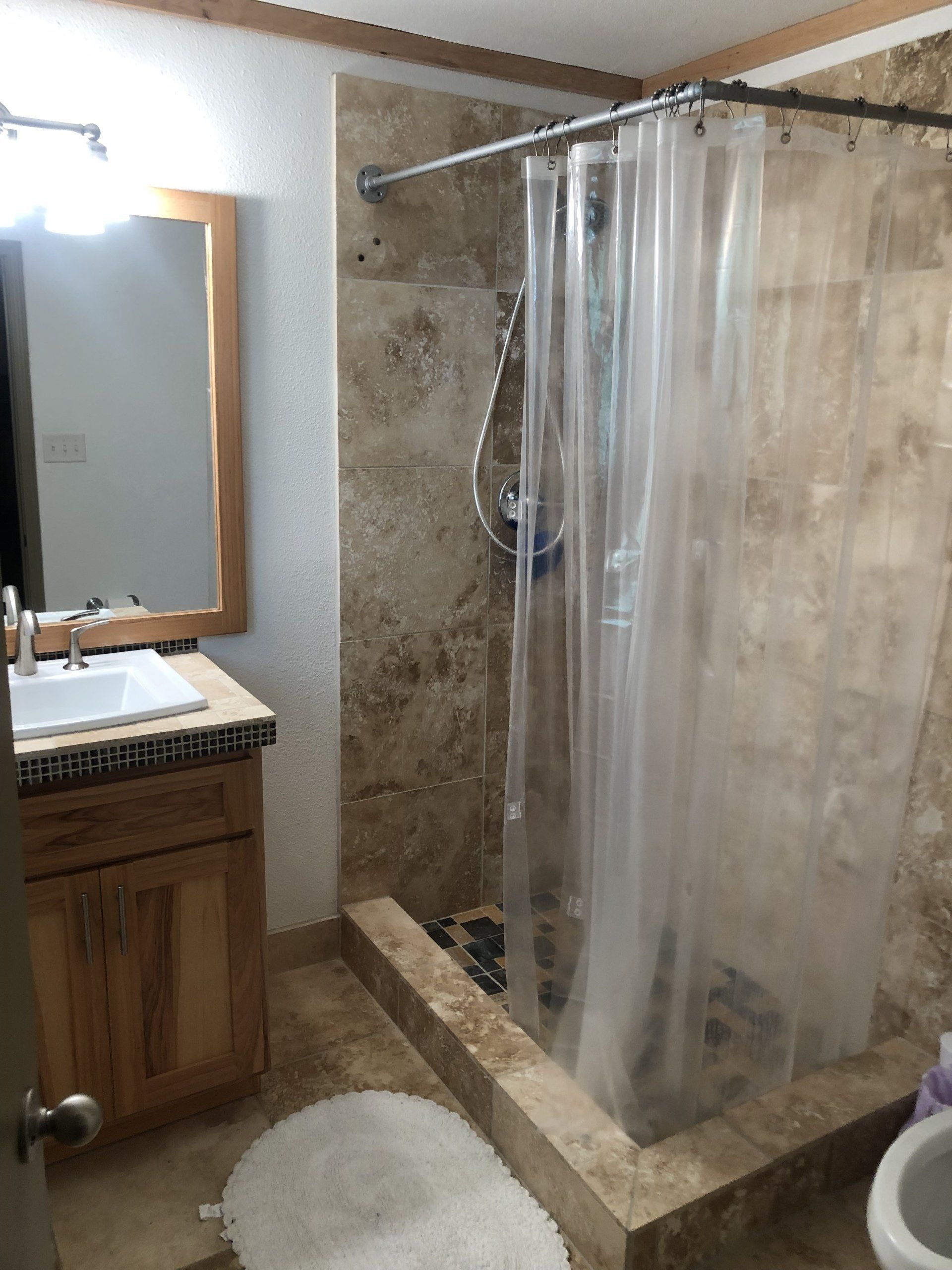 A bathroom with a clear shower curtain and a toilet