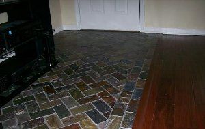 A living room with a brick floor and a wooden floor.
