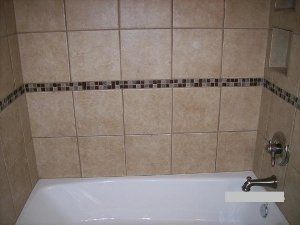 A bathtub in a bathroom with tiled walls and a faucet.