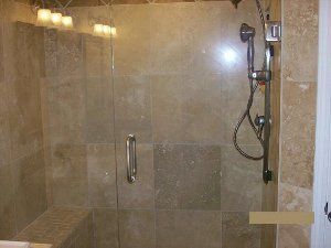 A bathroom with a walk in shower with a glass door and a shower head.