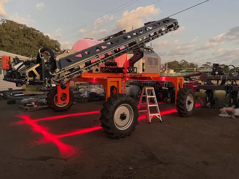 A large tractor is parked in a parking lot with a ladder next to it.