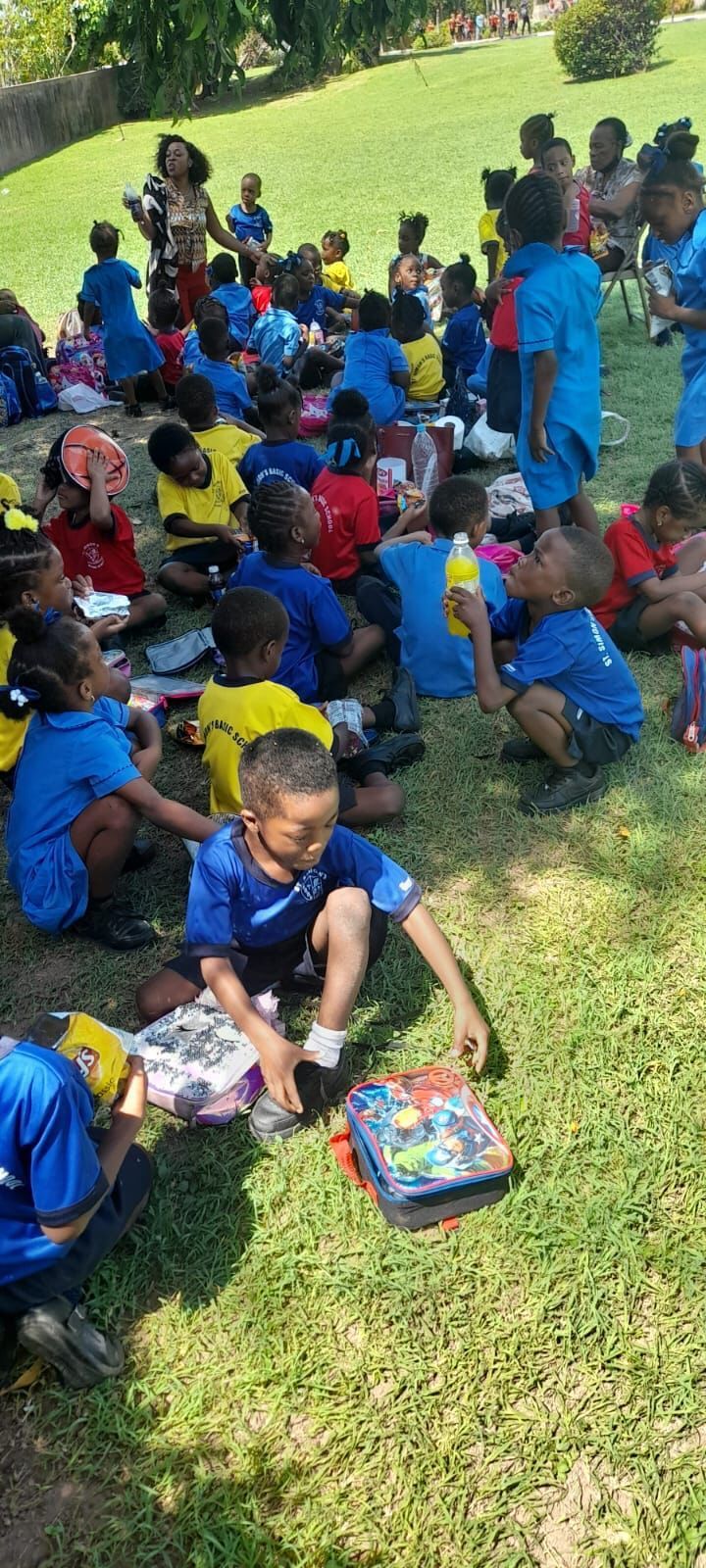 A group of children are sitting on the grass in a park.