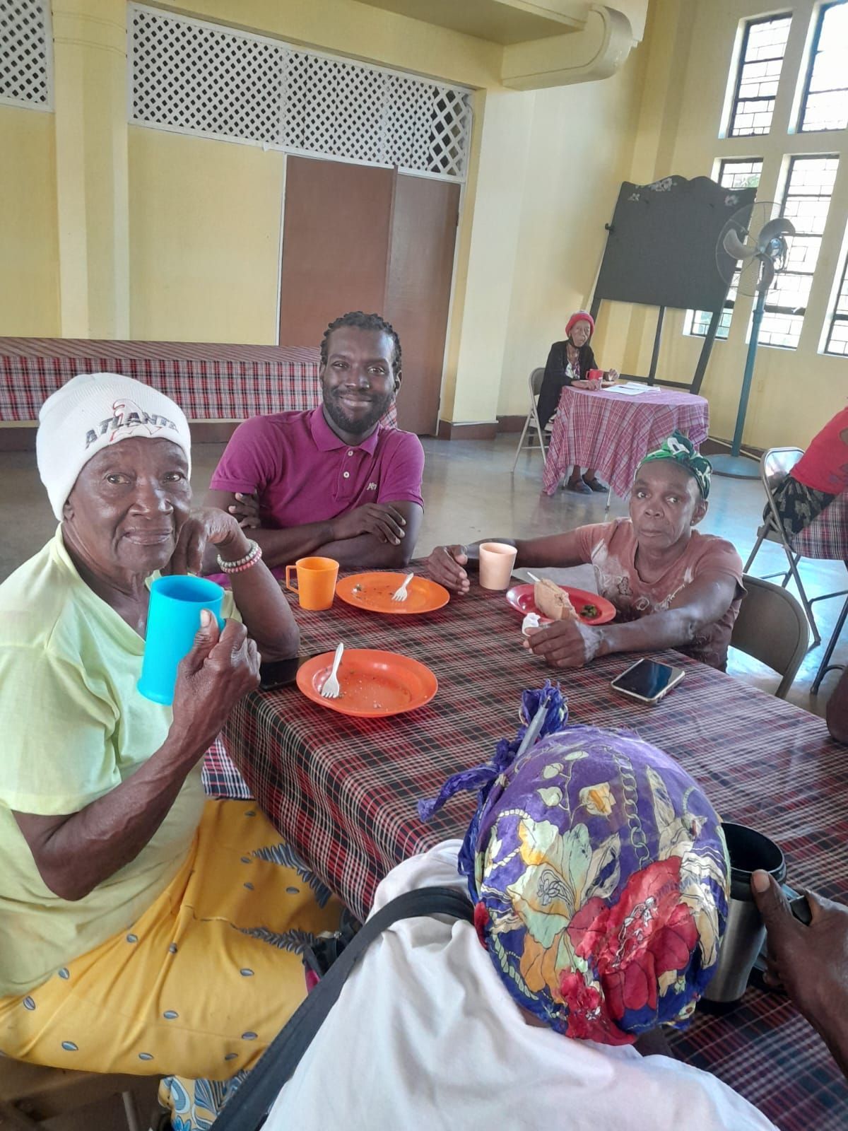 A group of people are sitting at a table with plates and cups.
