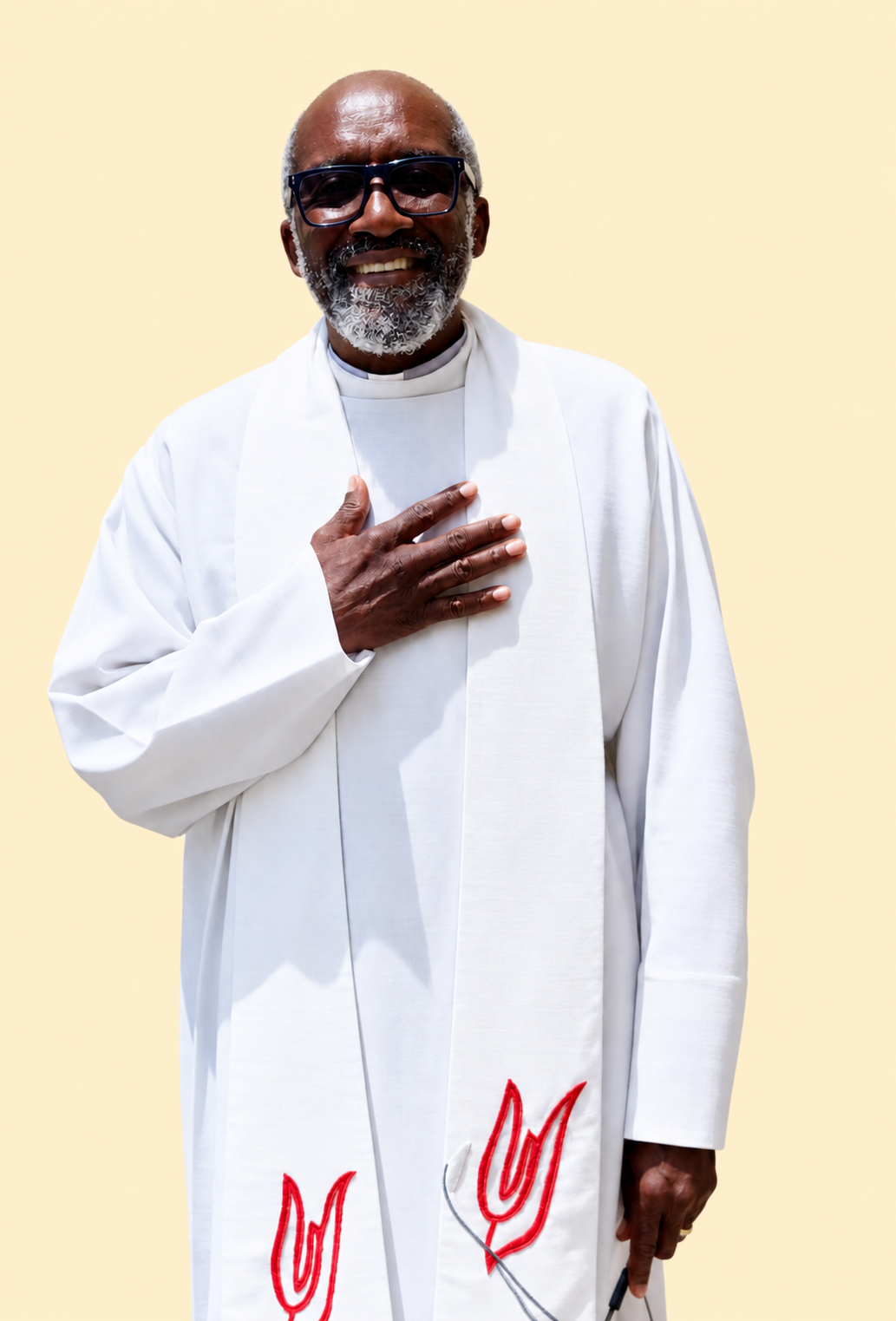 Smiling man in a white robe with red embroidery, hand over chest, standing against a beige background