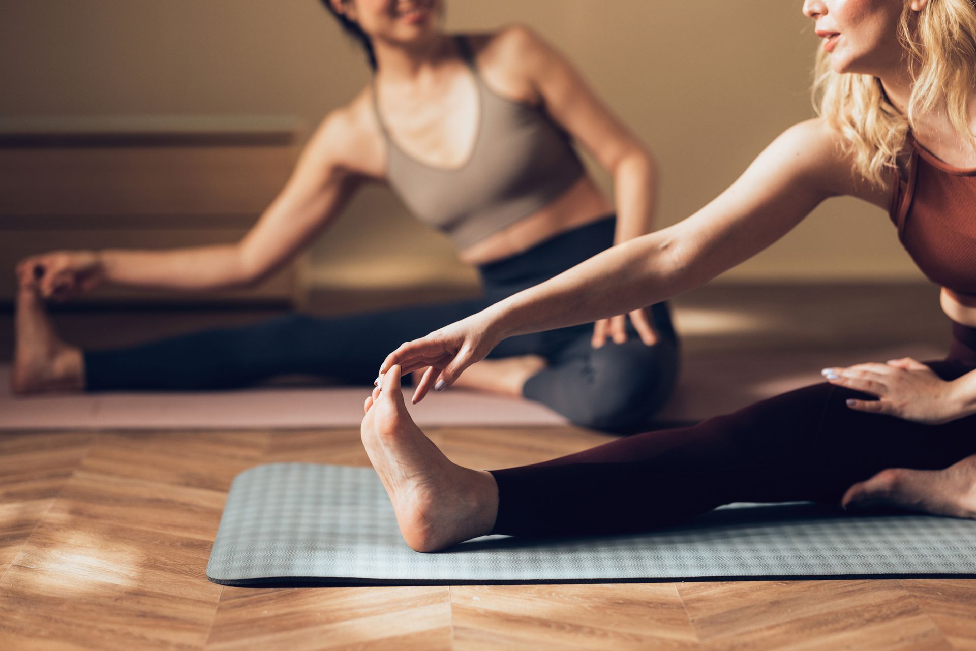 Due donne stanno allungando le gambe su un tappetino da yoga.