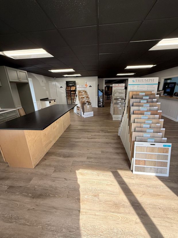 White kitchen with island, cabinets, countertops, stainless steel appliances, and wood flooring.