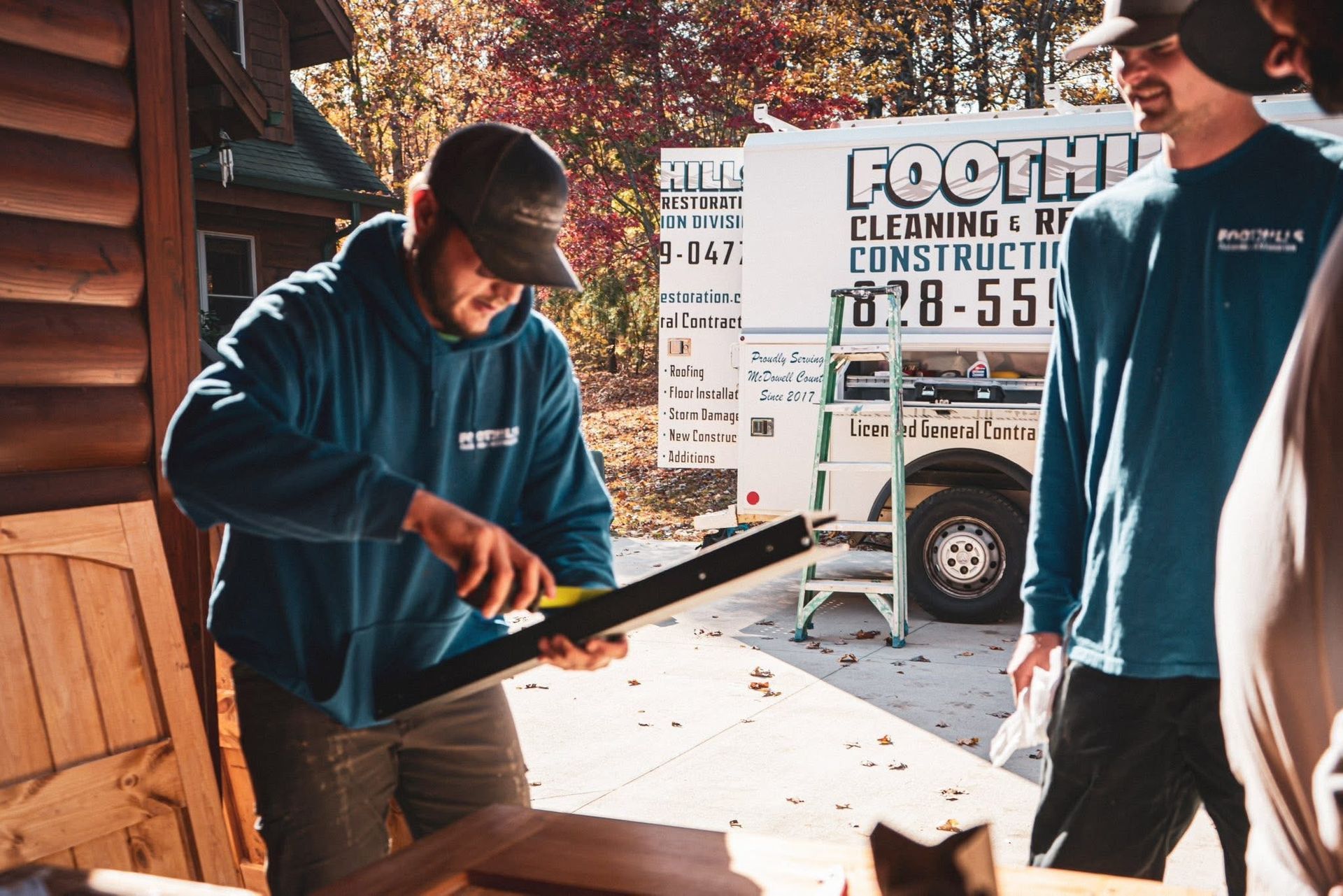 Two people shaking hands over a desk with construction tools and hard hats.
