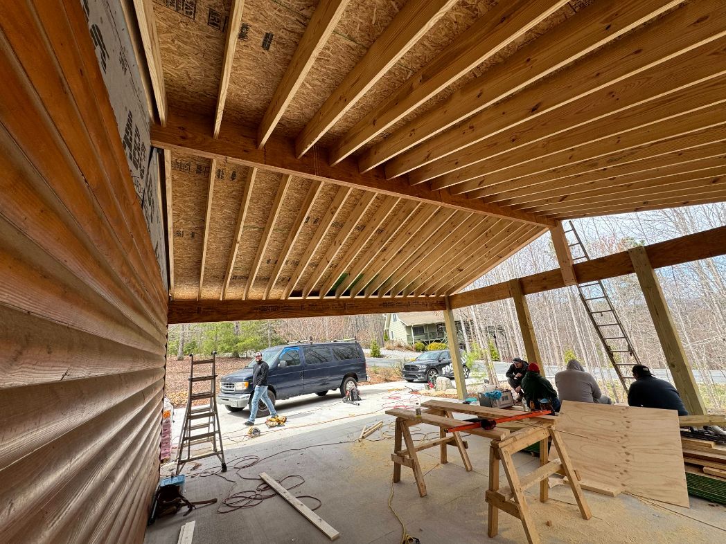 Wooden roof under construction with workers, tools, and a truck outside in daylight