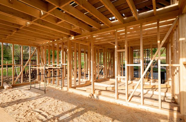 Wooden frame of a building under construction, with beams and open walls.