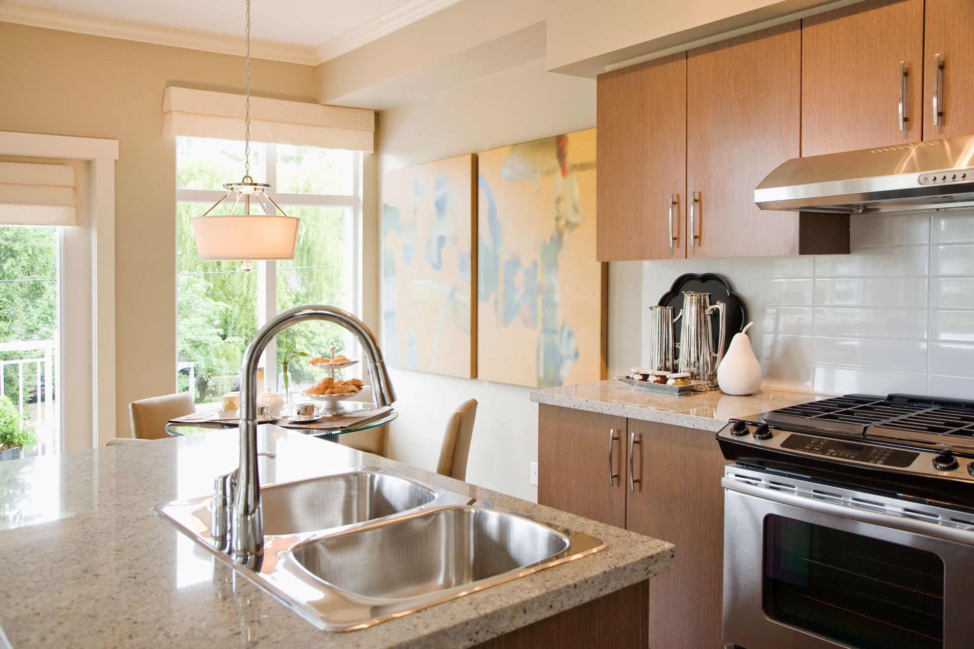 Kitchen with stainless steel appliances, light wood cabinets, and a granite countertop island with a double sink.