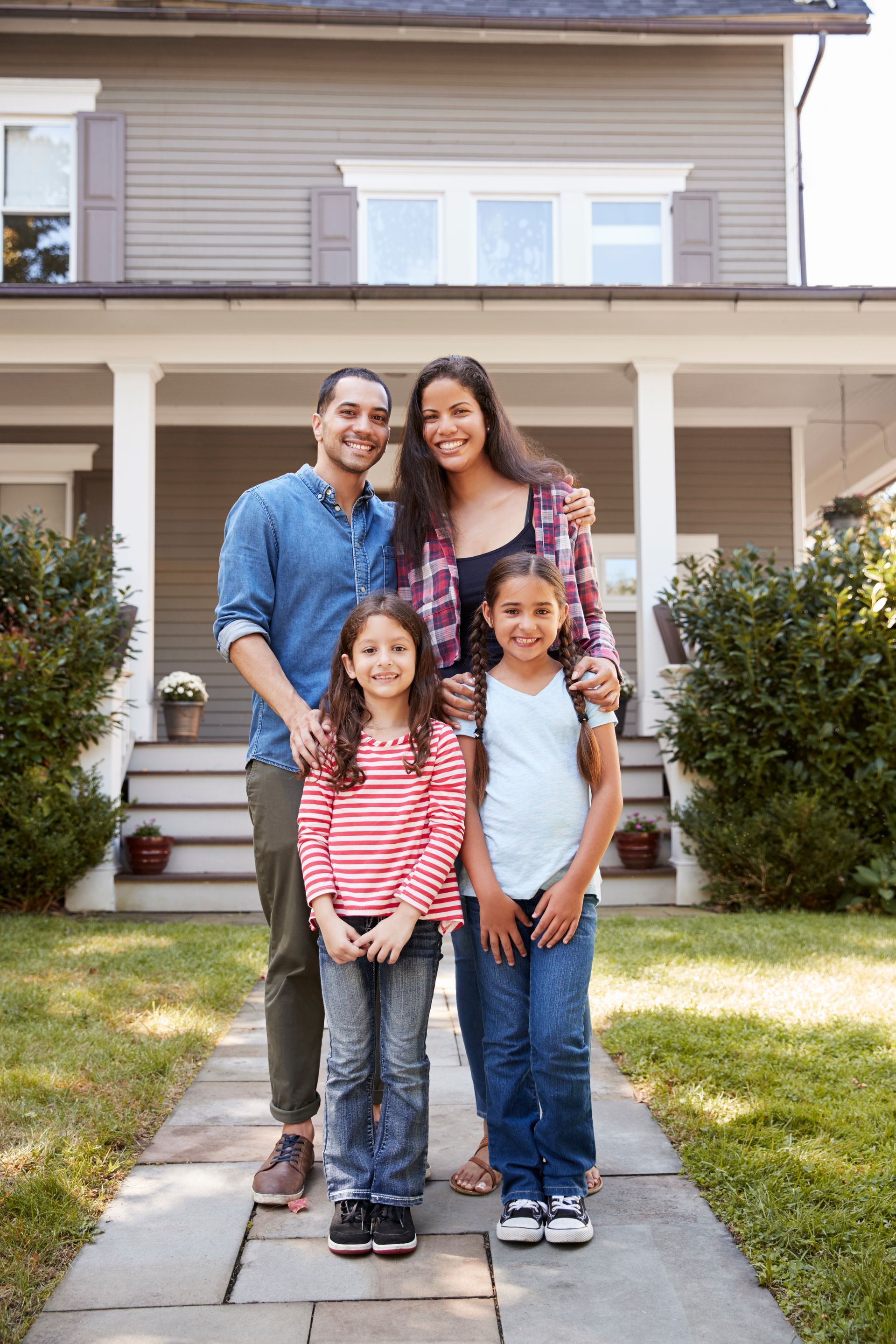 Family of four standing in front of their house.