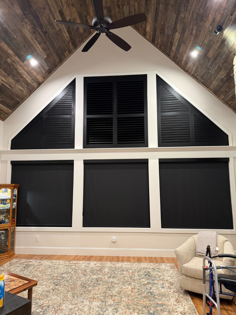 Living room with black shades, shutters, and wood ceiling.