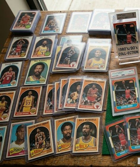 Spread of vintage baseball cards in plastic sleeves and a binder on a table, with colorful player portraits.