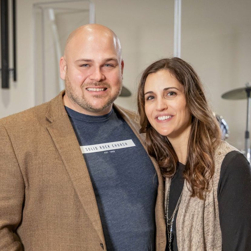 A bald man and a woman are posing for a picture together