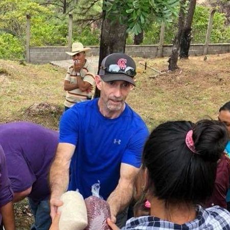 A man in a blue shirt is giving a bag of food to a woman.