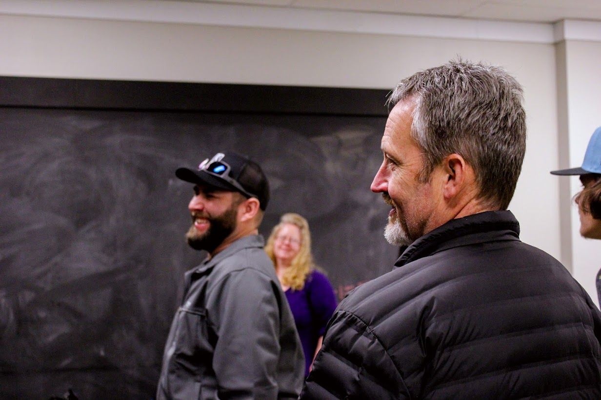 A group of men are standing in front of a blackboard in a room.