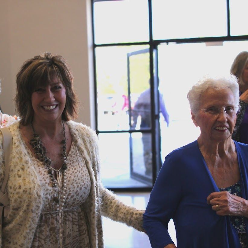 Two older women are standing next to each other and smiling