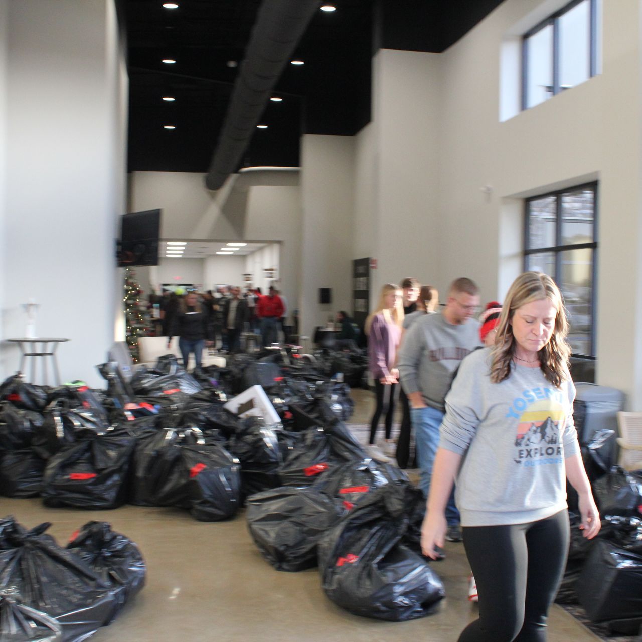 A woman wearing a sweatshirt walks through a room full of bags full of toys for our Hope For The Holidays Christmas ministry