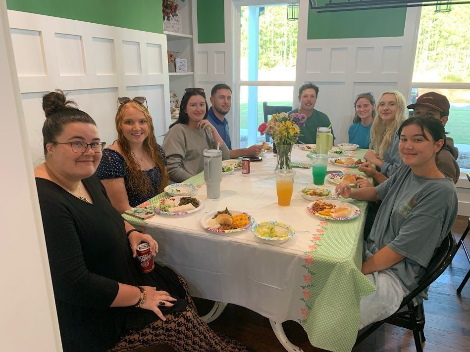 A group of people are sitting around a table with plates of food.