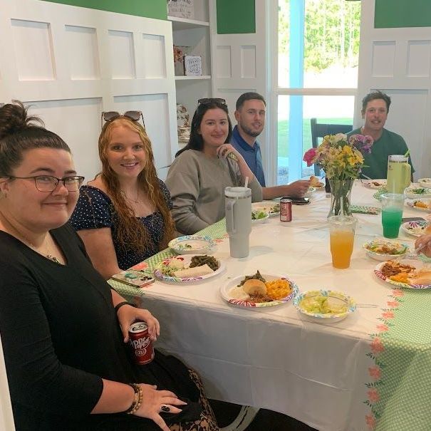 A group of people are sitting at a table with plates of food and drinks.