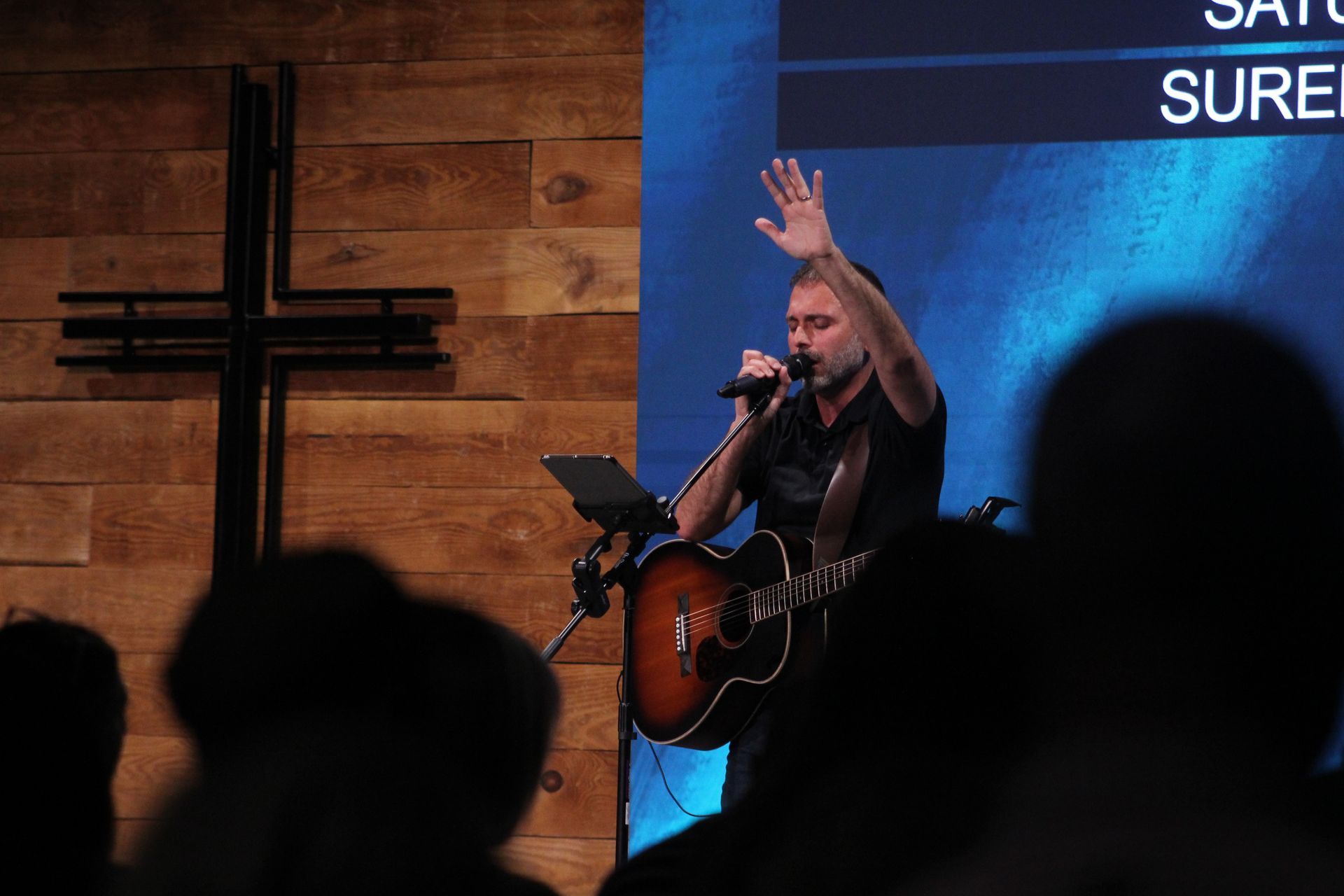 A man is singing into a microphone while holding a guitar.